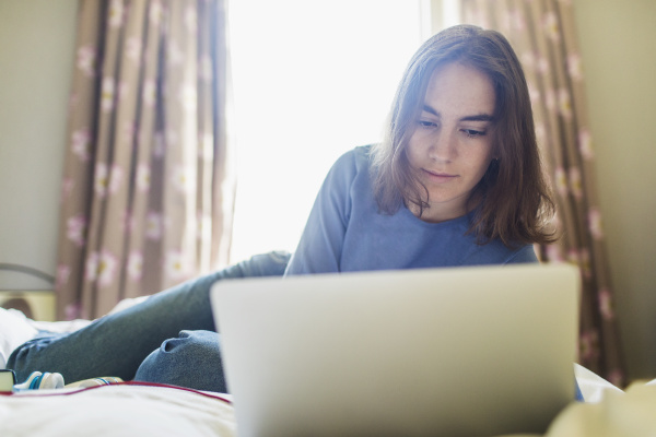 nastolatka korzystajaca z laptopa na lozku
