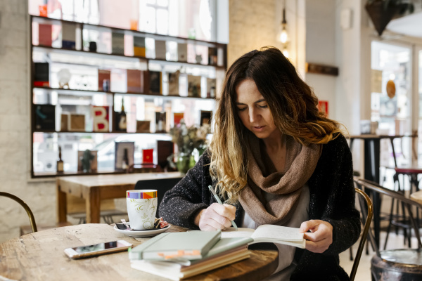 kobieta piszaca w notatniku w kawiarni