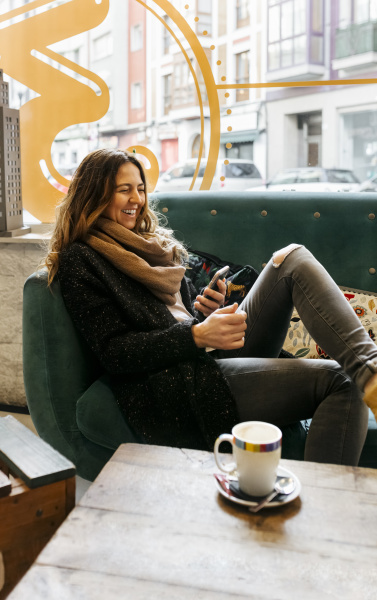 Smiejaca sie kobieta korzystajaca ze smartfona